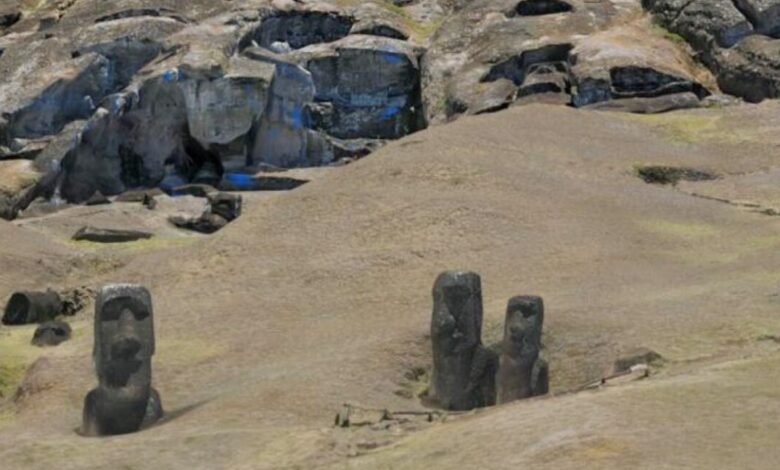 Moai statues stand on Easter Island against a rocky hillside.