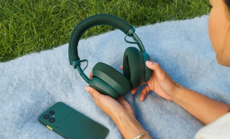 Green headphones and phone on a blue blanket outdoors.