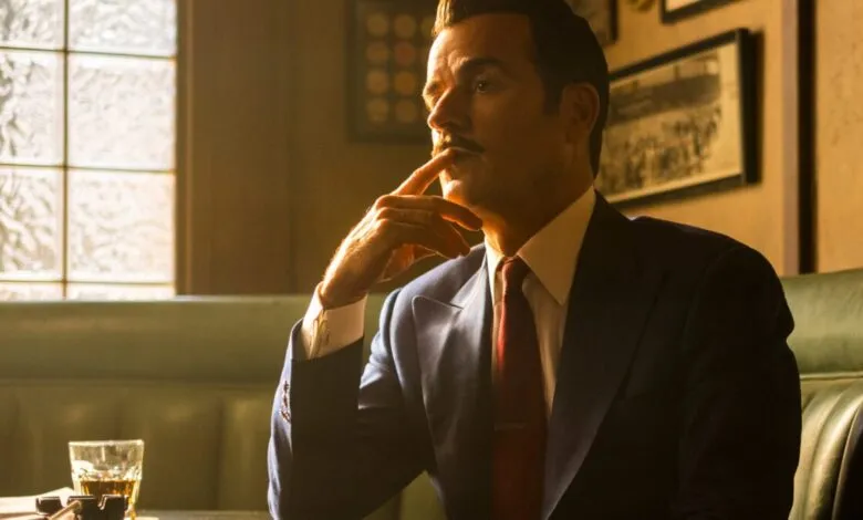 Man in suit with mustache thoughtfully posed indoors.