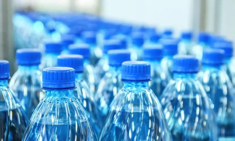 Rows of clear plastic water bottles with blue caps.