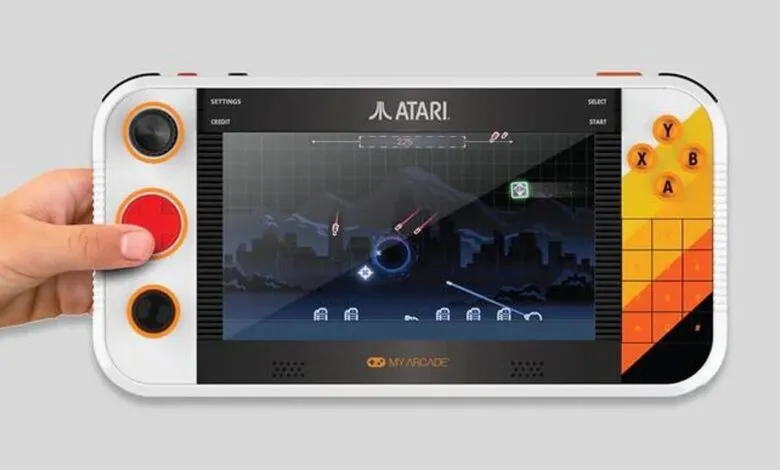 Hand holding Atari retro handheld gaming device with a game displayed.