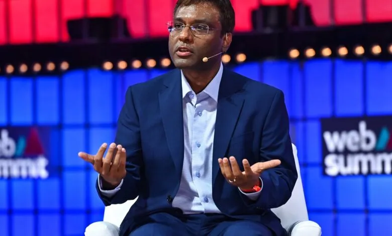 Man in suit gestures while speaking at Web Summit conference.