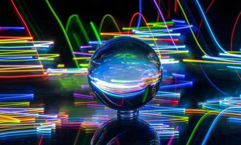 Crystal ball reflects colorful light trails on a dark surface.