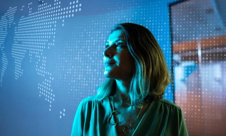 Woman looks up against a digital world map and binary code backdrop.