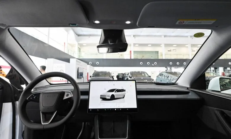 Tesla interior view from driver's seat, showing dashboard and touchscreen.