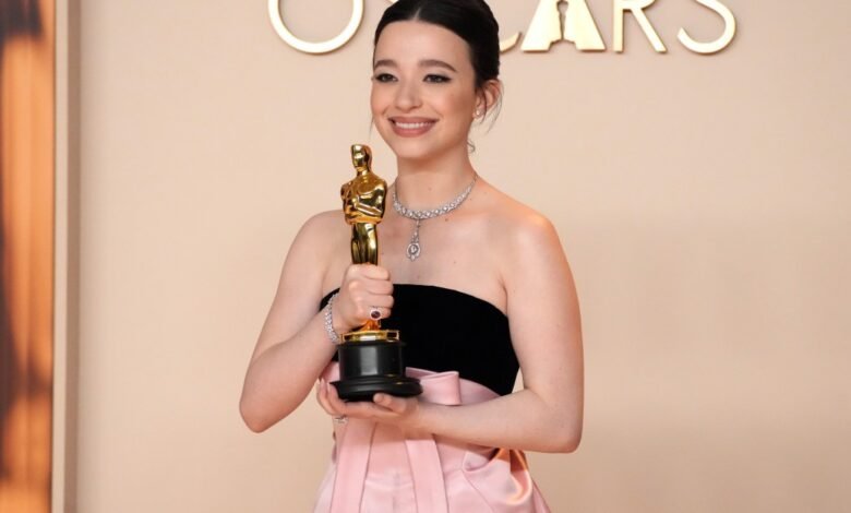 Talulah Riley smiles, holding her Oscar award.