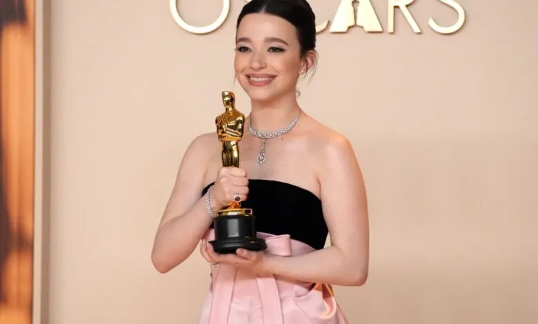 Talulah Riley smiles, holding her Oscar award.