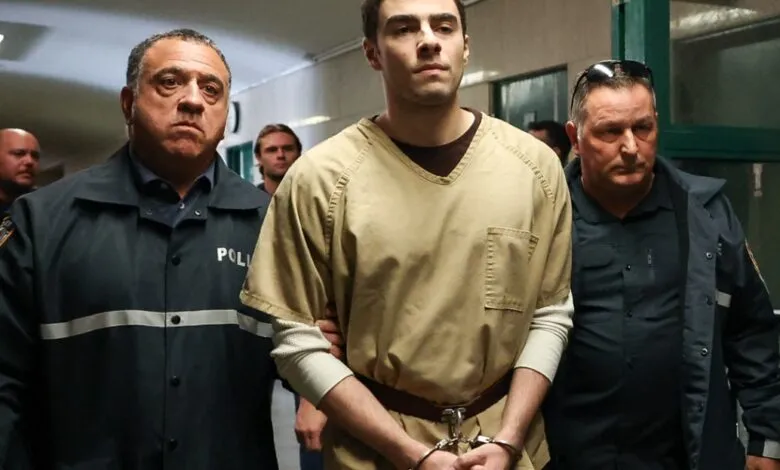 Man in prison uniform escorted by two police officers.