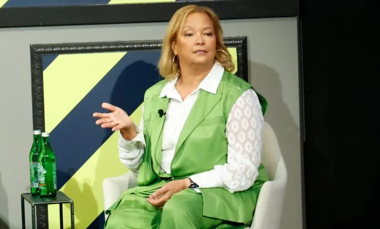 Rosalind Brewer speaks at event, wearing green suit.