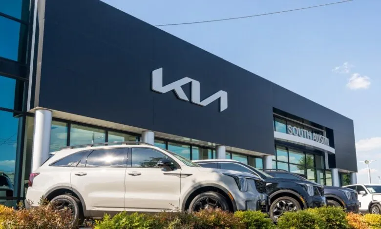 Exterior of Kia dealership with cars parked in front on a sunny day.