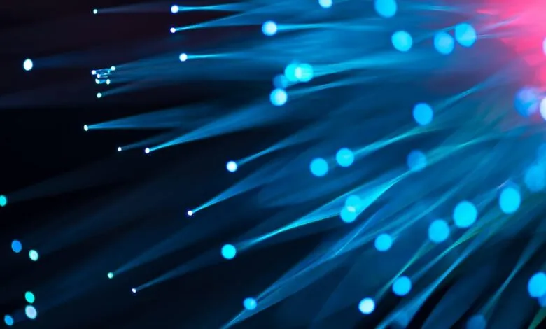 Abstract fiber optic strands glowing blue and pink against a dark background.
