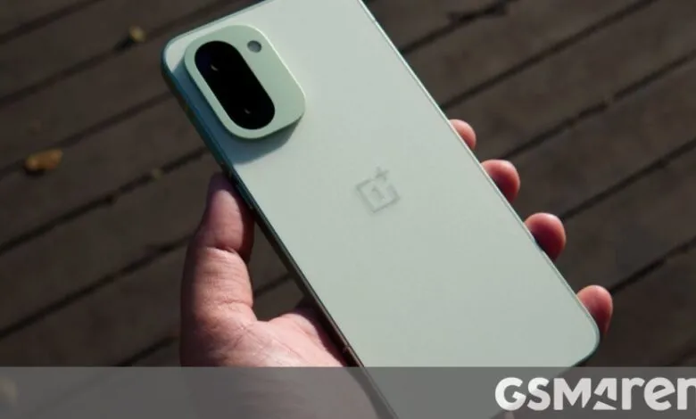 Hand holding a light green OnePlus phone, showing the camera.