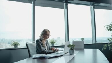 Businesswoman working on laptop in modern office with city view.