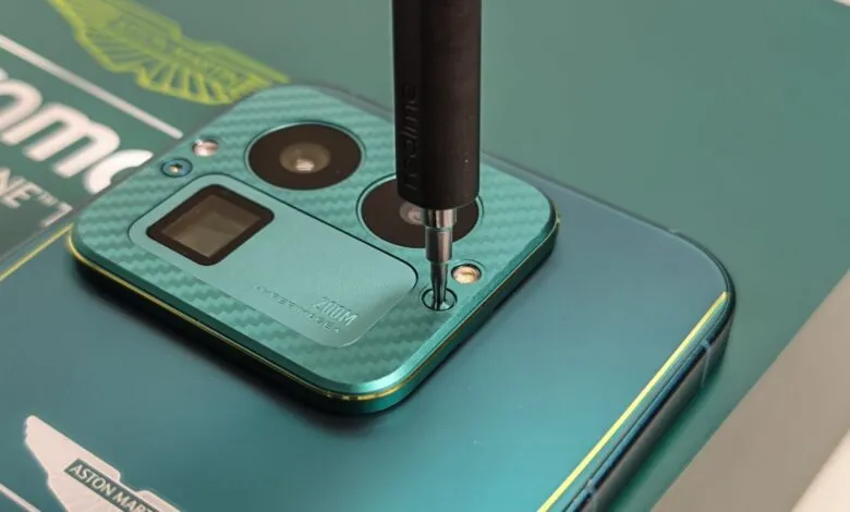 Close-up of a Realme phone with Aston Martin branding being repaired.