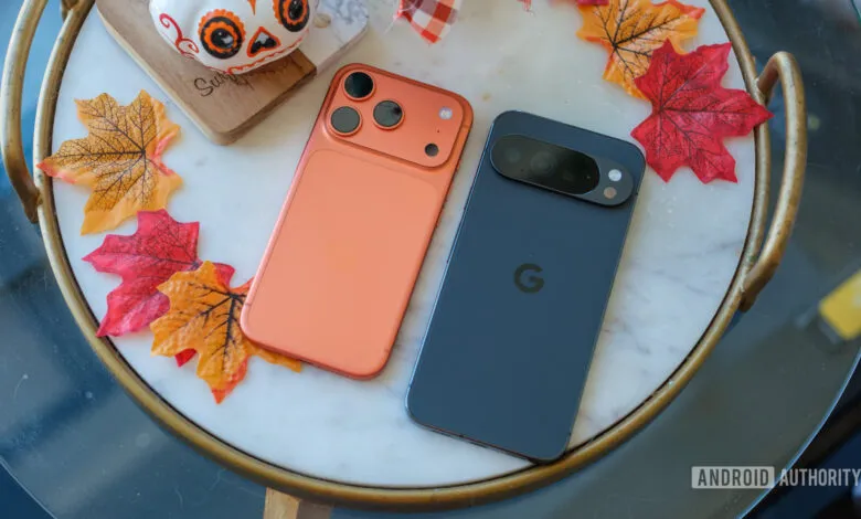 Orange iPhone and blue Pixel phone on a marble table with fall leaves.