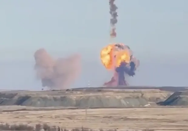 Large explosion with smoke plumes rising from a barren landscape.