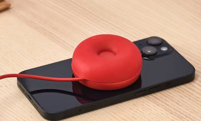 Red donut-shaped cable organizer sits on a black smartphone.
