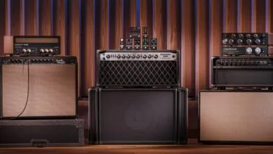 Collection of guitar amplifiers and effects pedals against a wood panel backdrop.