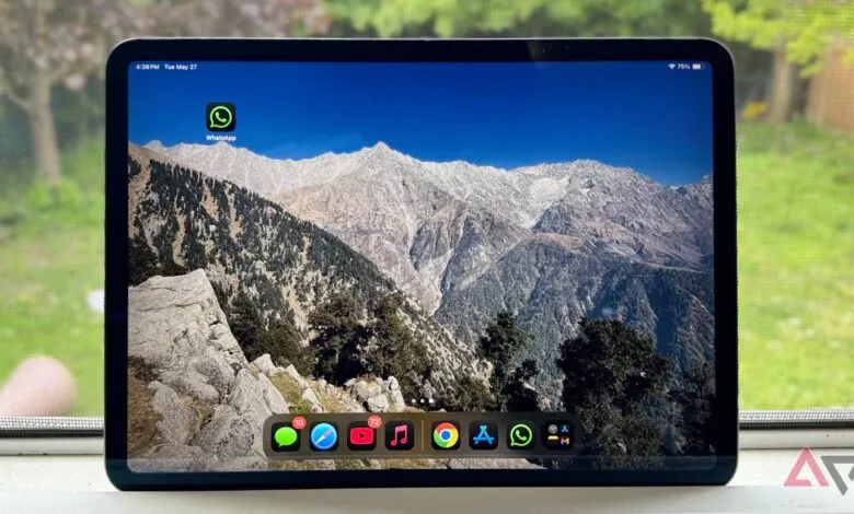 iPad displaying WhatsApp icon and mountain wallpaper on home screen.