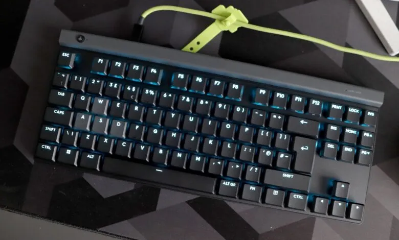 Mechanical keyboard with blue backlighting on a geometric patterned desk mat.