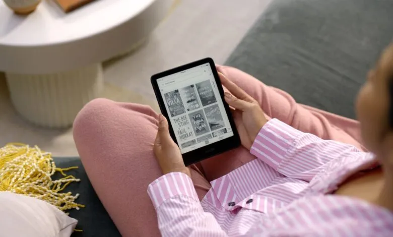 Person relaxing with Kindle e-reader showing book covers.