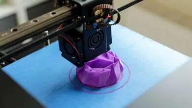 3D printer creating a purple geometric object on a blue surface.
