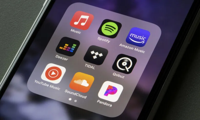 Phone screen displaying music streaming app icons like Spotify, Apple Music, and Pandora.