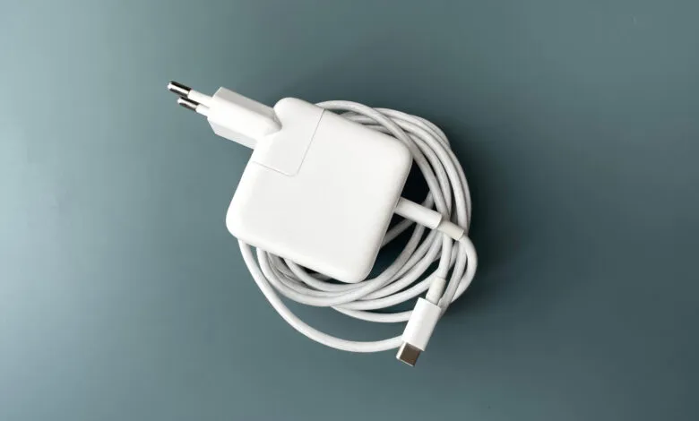 White USB-C power adapter with coiled cable on a blue background.
