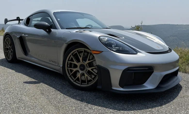 Silver Porsche 718 Cayman GT4 RS with bronze wheels parked on asphalt.
