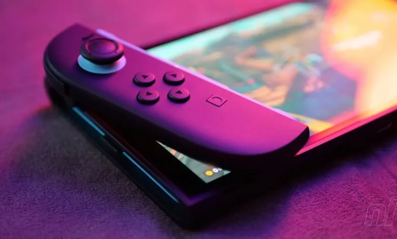 Close-up of a Nintendo Switch with Joy-Con attached, lit with purple and pink hues.