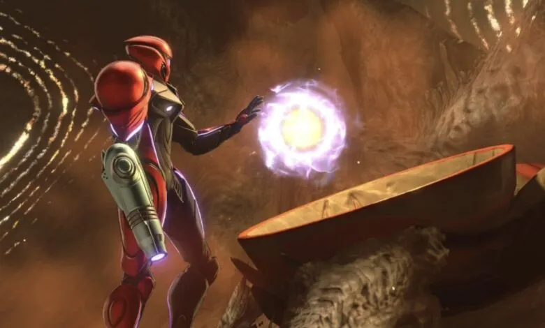 Samus Aran in red suit reaches for glowing energy ball in cavernous space.