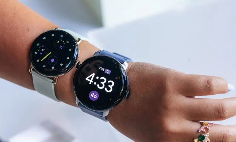Two smartwatches on a wrist, one with a light band and one with a blue band.