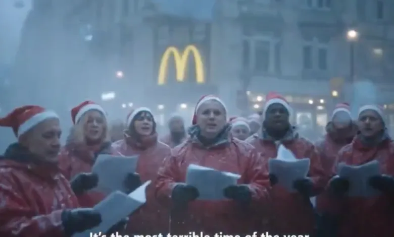 Carolers in Santa hats sing in front of a McDonald's during snowy weather.