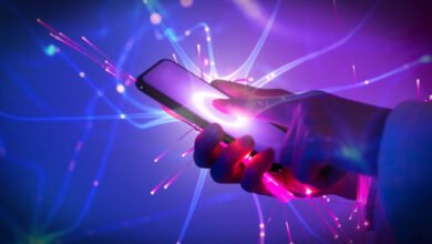 Hand holding smartphone with glowing interface and fiber optic effects.