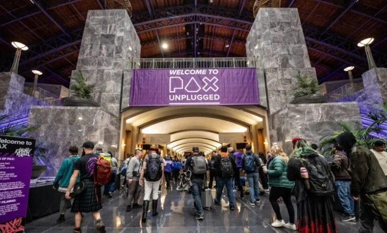 Attendees enter PAX Unplugged gaming convention under a 'Welcome' banner.