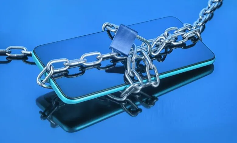 Smartphone secured with chain and lock on reflective blue surface.