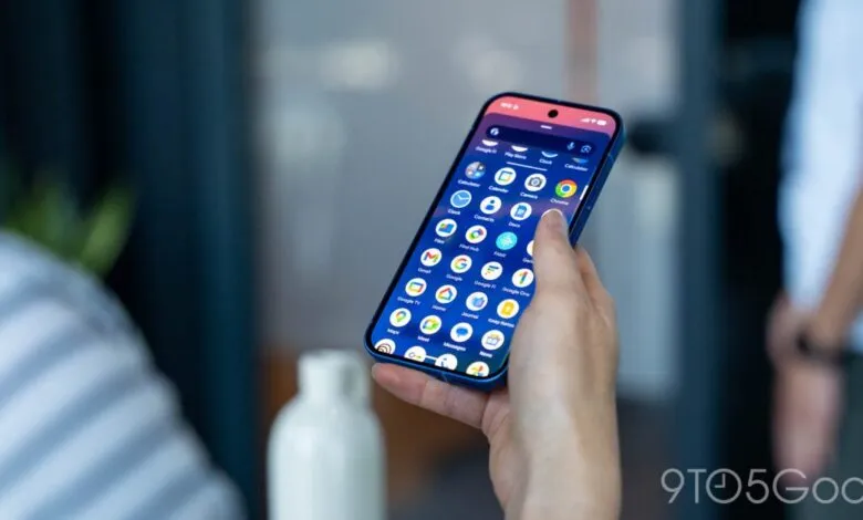 Person holding a blue smartphone displaying app drawer interface.