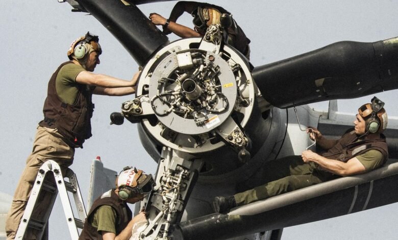 Military personnel repair aircraft engine on the flight deck.