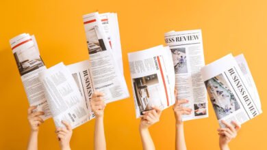 Hands holding business newspapers against a bright yellow background.
