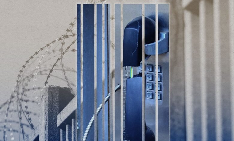 Prison phone behind bars with barbed wire, conveying isolation.