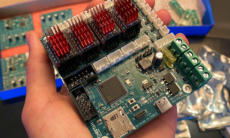 Hand holding a Cheetah MX4 Mini circuit board with red heat sinks.