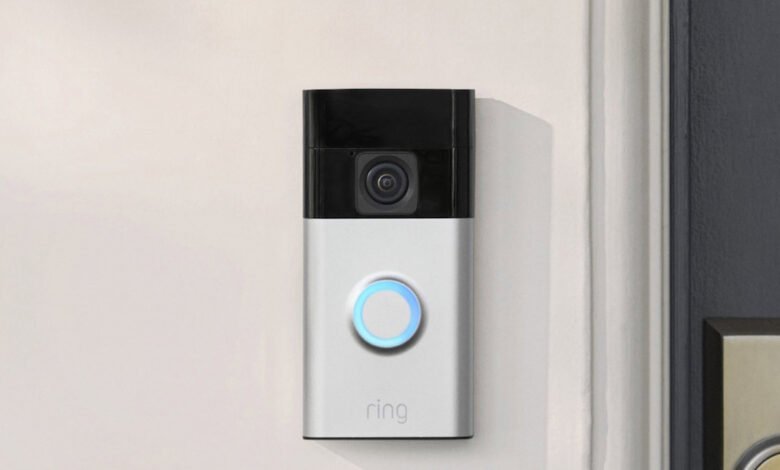 Ring video doorbell mounted on a white wall next to a dark door.