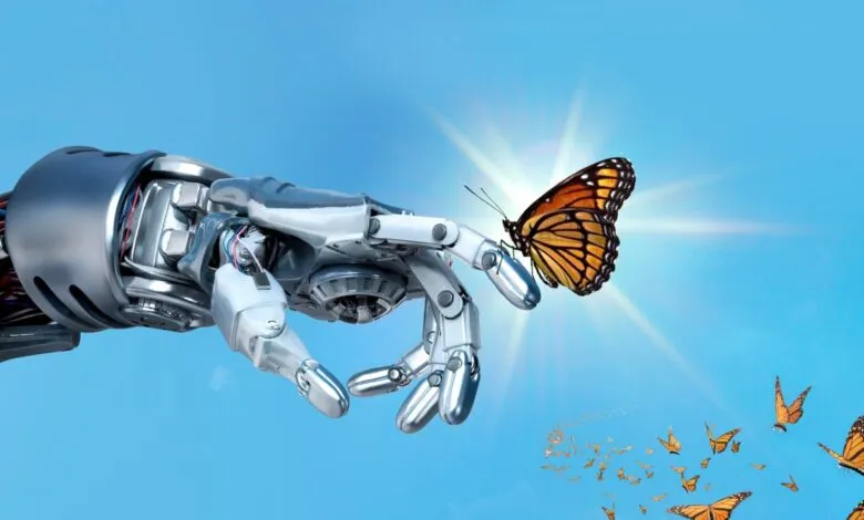 Robot hand gently holding a monarch butterfly against a blue sky.
