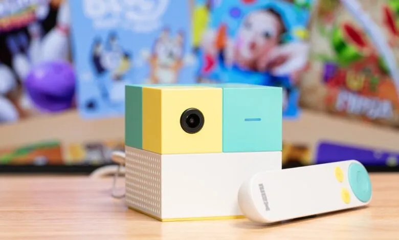 NEX Playground device with remote on a wooden surface, colorful background.