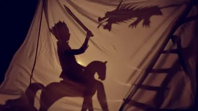 Shadow puppet show of a king on horseback fighting a dragon.