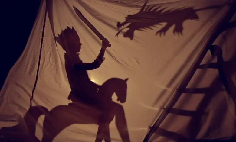 Shadow puppet show of a king on horseback fighting a dragon.