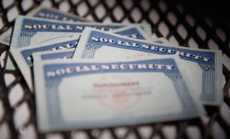 Several Social Security cards stacked on a metal grate.