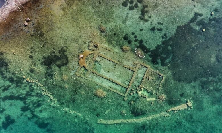 Aerial view of submerged basilica ruins in clear turquoise lake water.