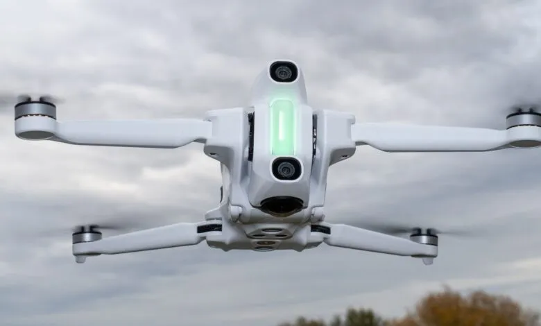 White drone with spinning propellers against cloudy sky.