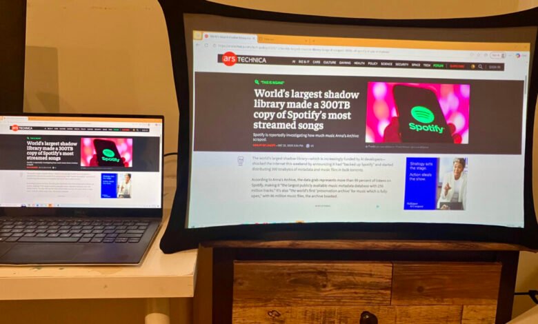 Laptop and curved monitor displaying Ars Technica article about Spotify data copy.